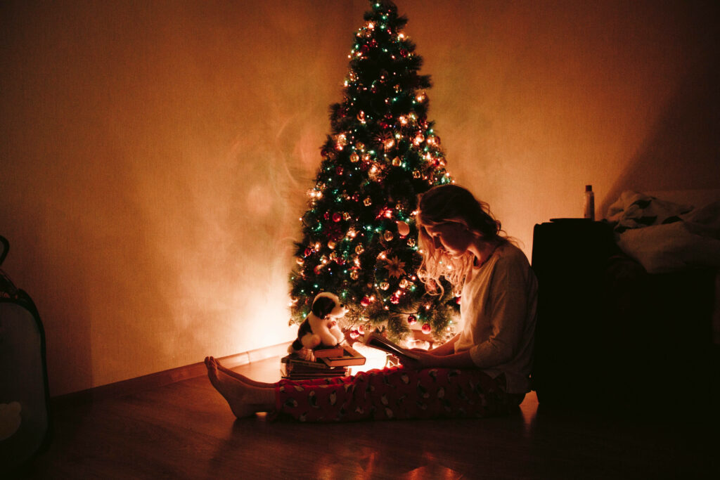Cozy Holiday Reading by a Decorated Christmas Tree Ambiance Wallpaper