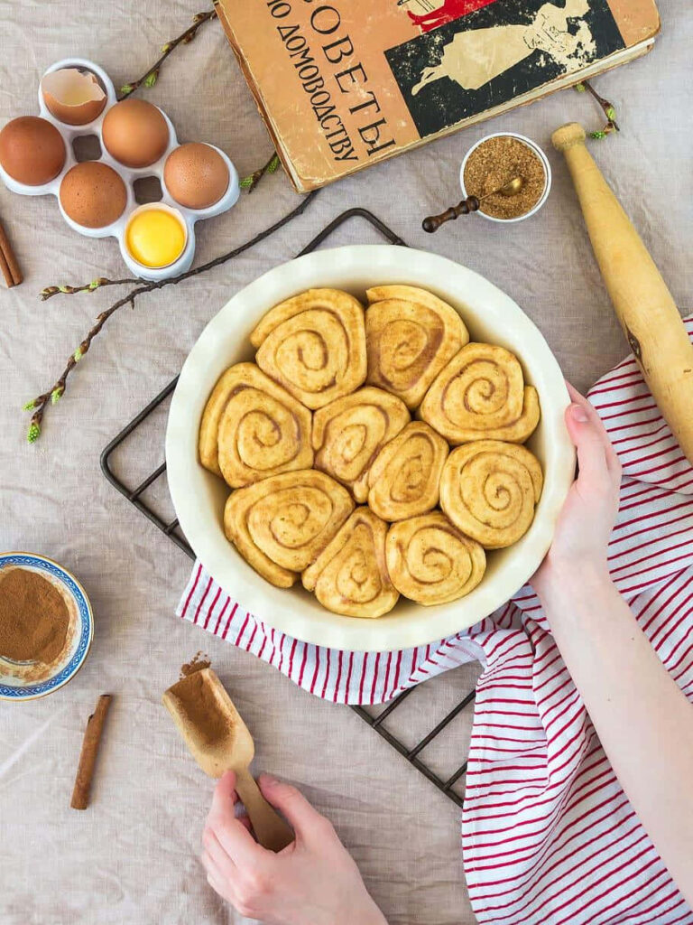Cozy cinnamon rolls dough in baking dish with eggs spices brown sugar rolling pin and cookbook Wallpaper