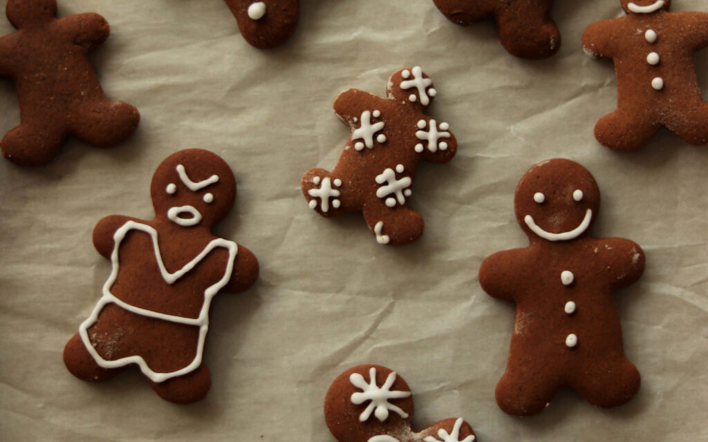 Assortment of decorated gingerbread cookies on parchment paper festive homemade holiday wallpaper