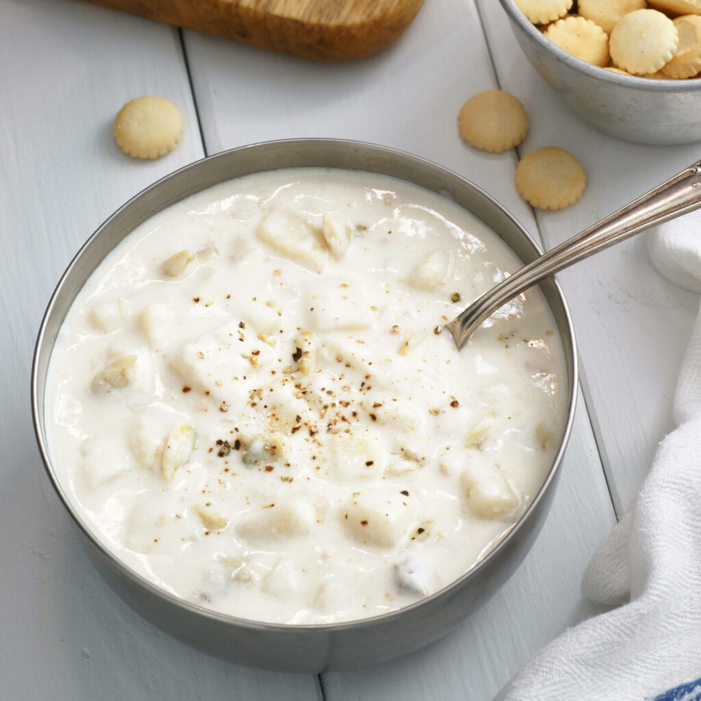 Creamy potato and clam chowder with black pepper and oyster crackers in rustic bowl background Wallpaper