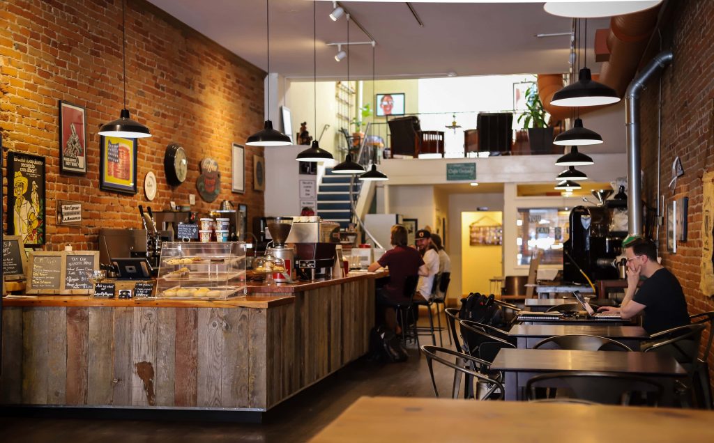 Cozy industrial coffee shop wallpaper with warm lighting exposed brick and rustic wooden counter