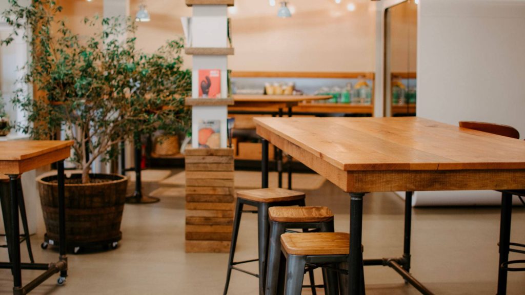 Cozy cafe wallpaper with industrial rustic wooden furniture warm lighting and potted tree background