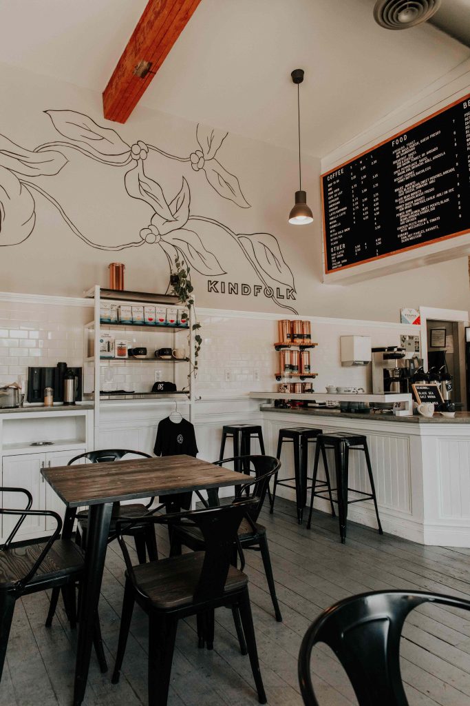 Cozy Kindfolk coffee shop interior with subway tiles leaf mural rustic menu black furniture wallpaper