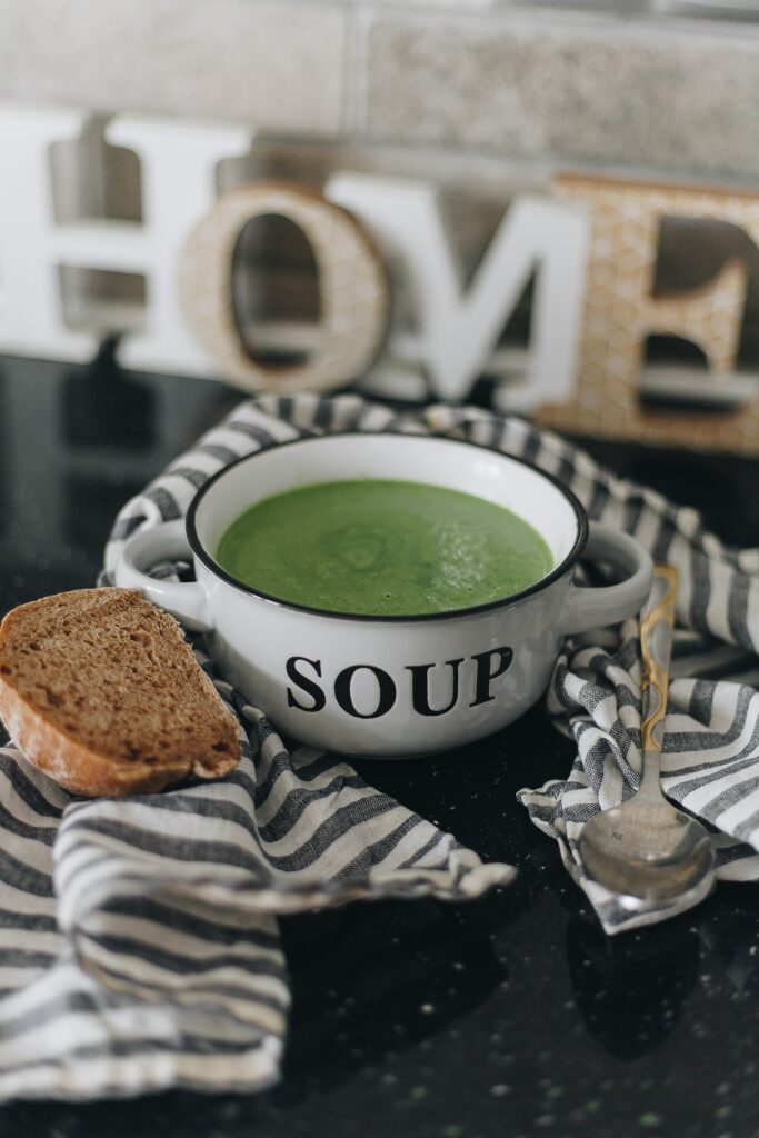 Cozy Kitchen Scene: Green Soup, Bread & Home Decor on Striped Cloth Wallpaper
