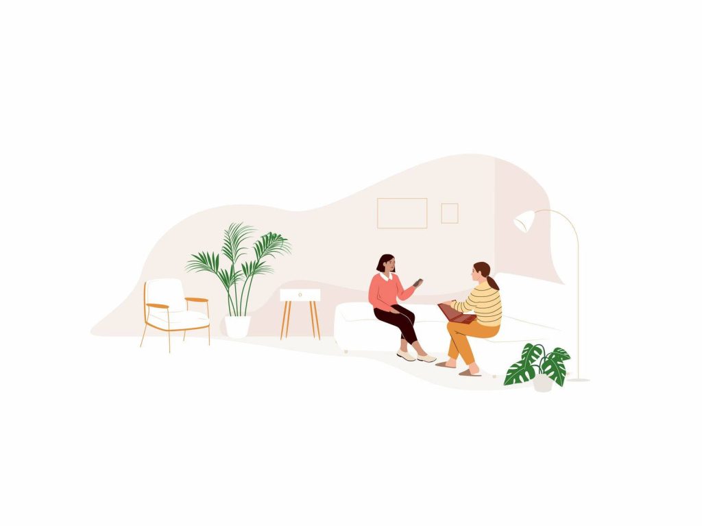 Two women collaborating on a laptop in a cozy modern home with plants and peach tones Wallpaper