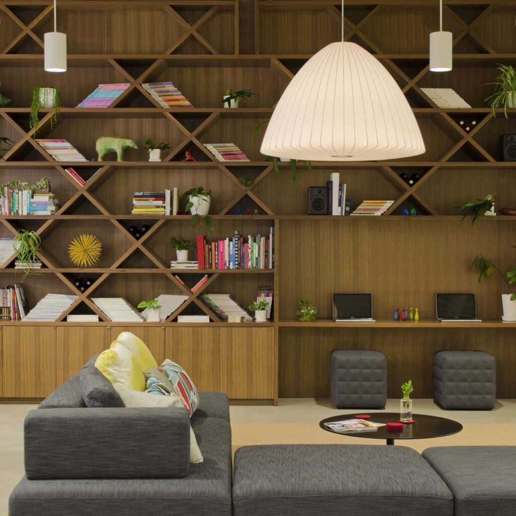 Cozy gray couch modern pendant lamp geometric wooden bookcase stylish home library wallpaper