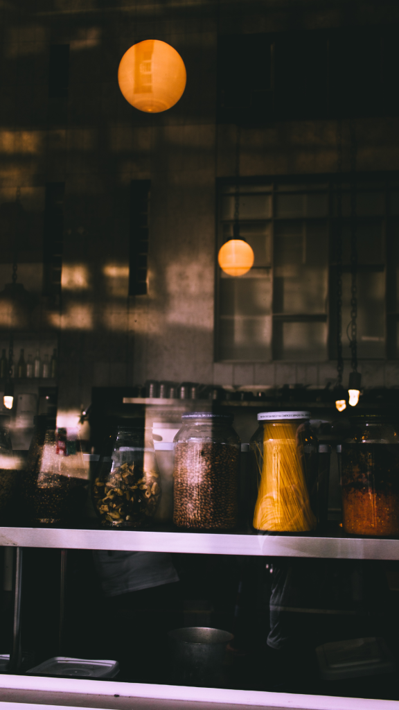 Cozy modern urban coffee shop interior with jars of pasta and beans under warm pendant lights Wallpaper