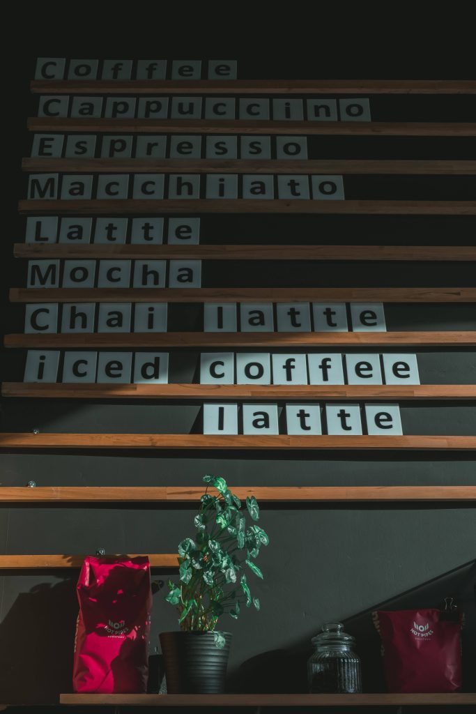 Moody coffee shop wallpaper with rustic menu board plant and Hot Pipes Roastery bags background