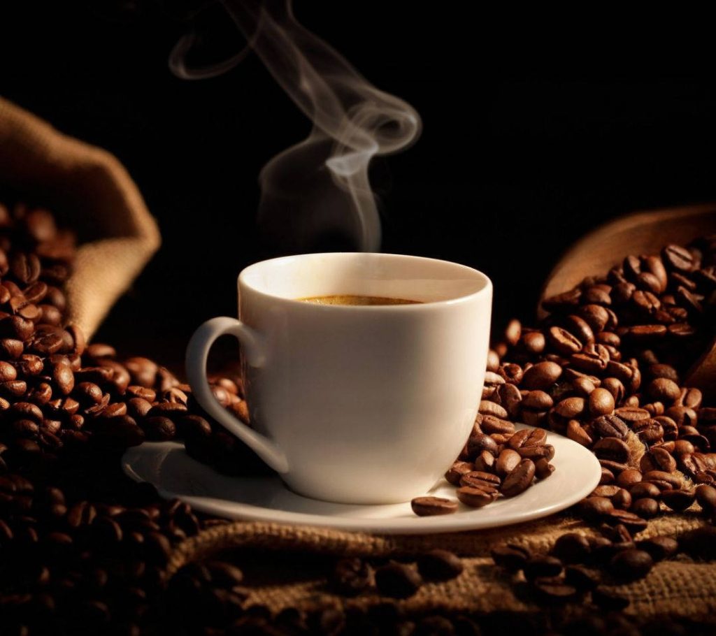 Steaming white coffee mug with roasted beans on burlap rustic dark background wallpaper