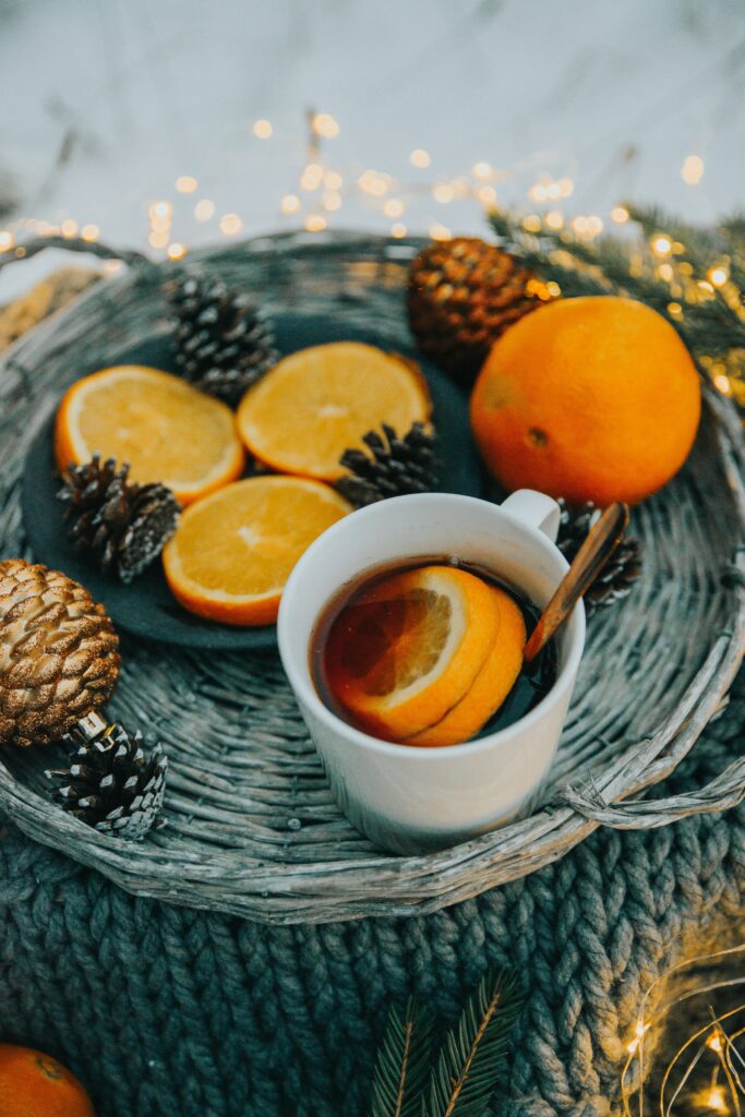 Cozy Christmas Tea Setup: White Mug, Oranges & Pinecones Wallpaper
