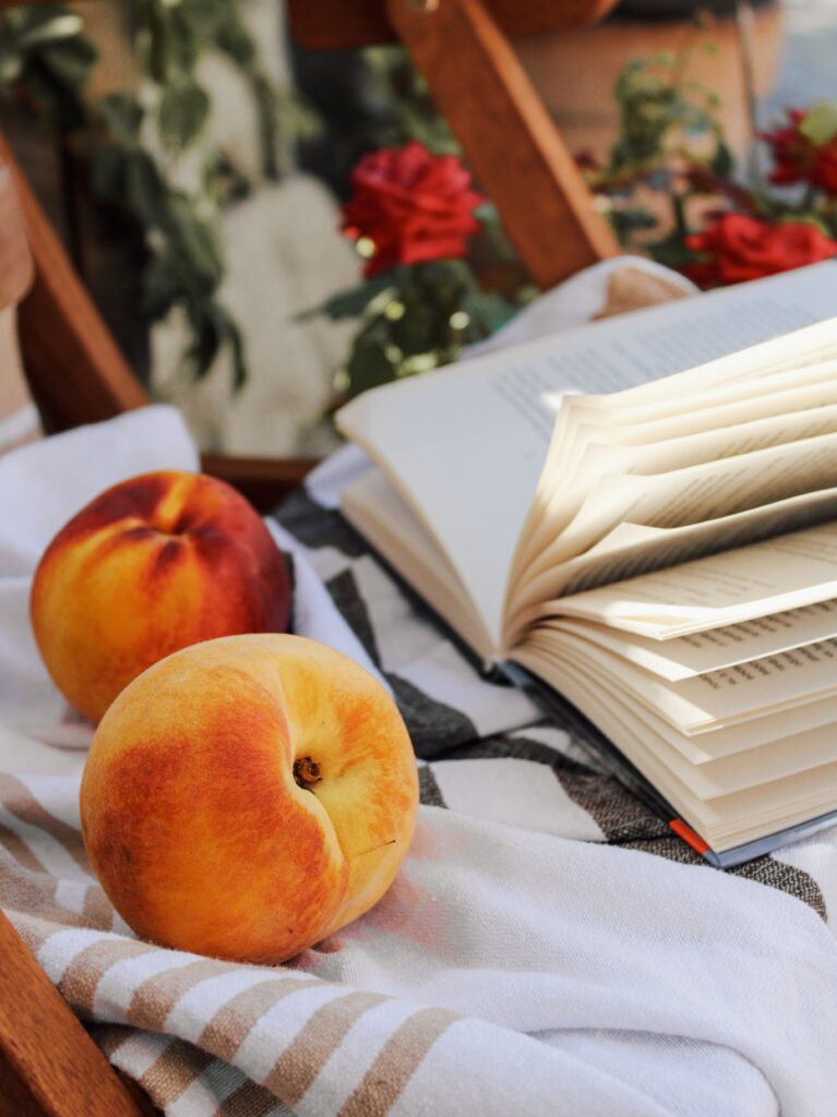 Cozy Outdoor Scene: Ripe Peaches & Book on Striped Cloth Wallpaper