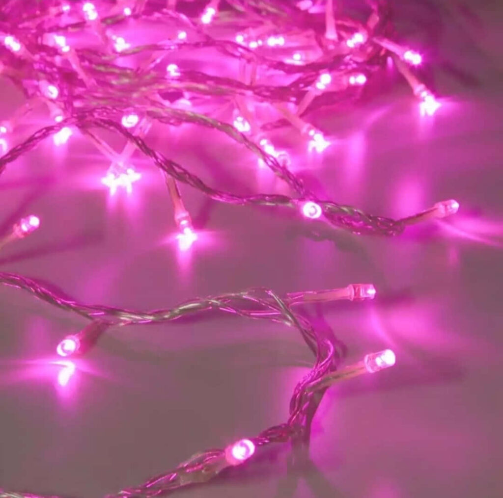 Pink LED string lights glowing softly on table creating warm inviting vibrant cheerful ambiance Wallpaper