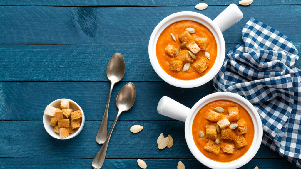 Vibrant Pumpkin Soup Wallpaper: Cozy Bowls on Rustic Table