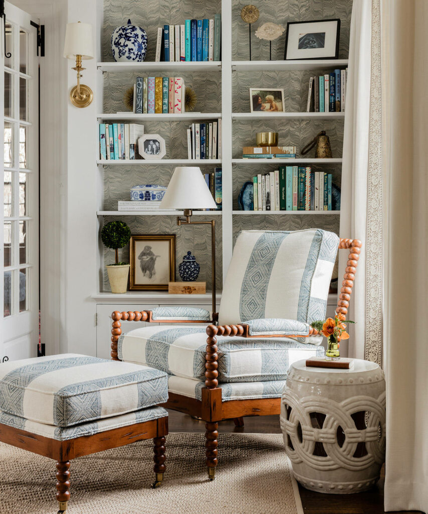 Cozy reading nook with built-in bookshelf colorful books patterned armchair and ottoman wallpaper wall