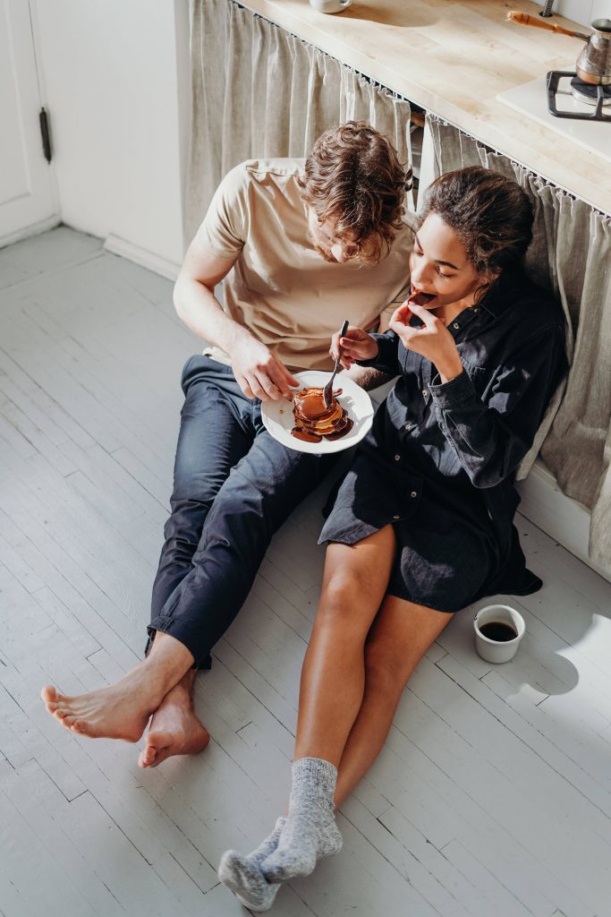 Couple sharing chocolate pancakes on white kitchen floor cozy romantic natural light wallpaper