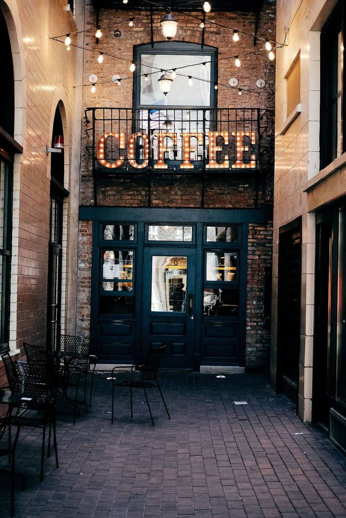Cozy coffee shop wallpaper with rustic alley brick walls black doors warm lights vintage sign