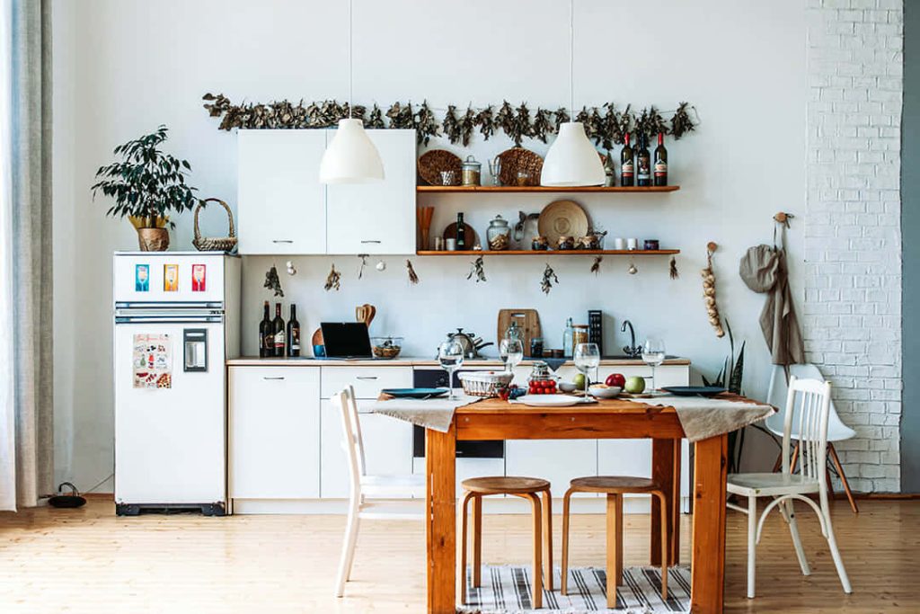 Rustic modern kitchen with white cabinets wooden floors pendant lights and hanging dried herbs Wallpaper