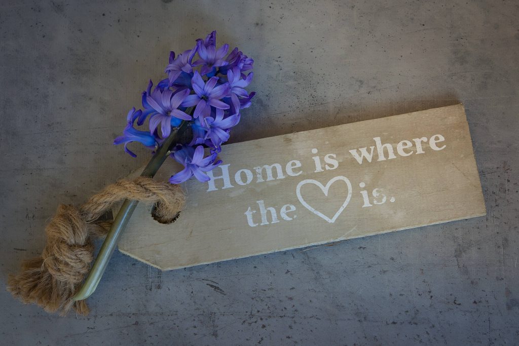 Rustic wallpaper with purple hyacinth flower and home heart wooden plaque on grey concrete
