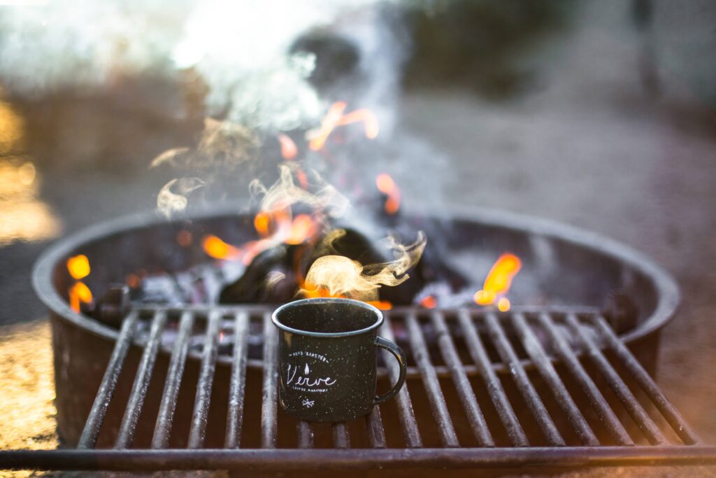Cozy Cup on Grill: Rustic Wallpaper with Warm Flames & Firewood