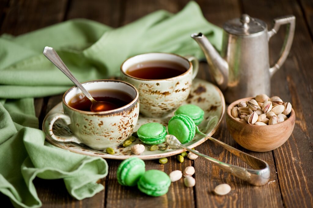 Cozy Still Life: Tea, Macarons & Vintage Teapot on Rustic Table Wallpaper