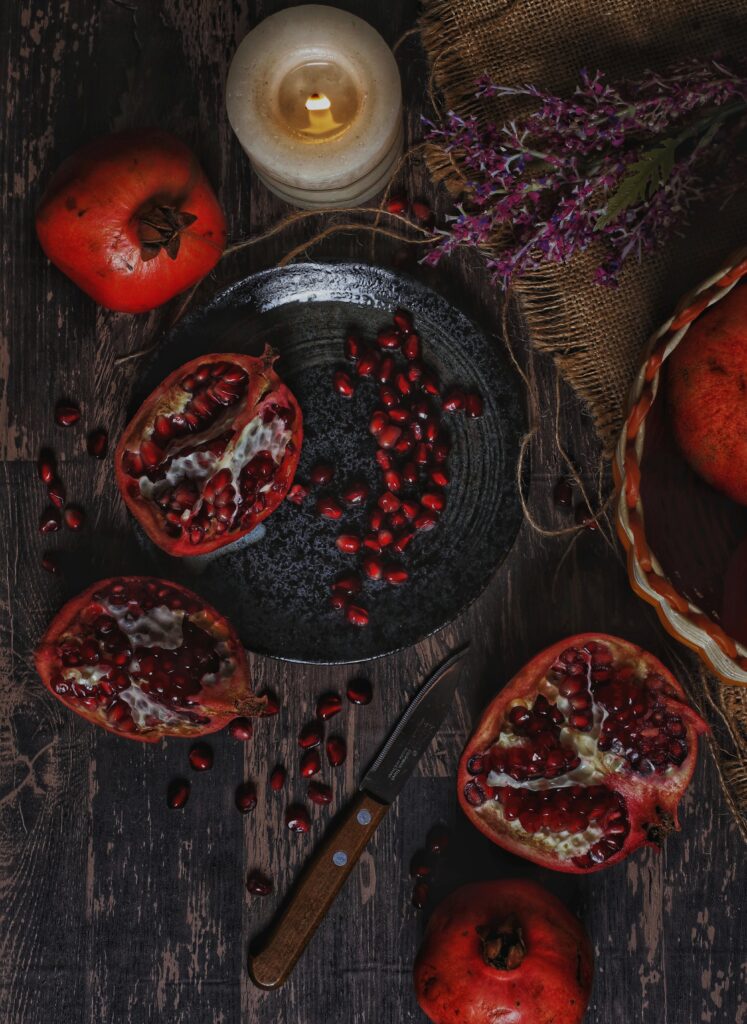 Warm Still Life: Ripe Pomegranates & Candle on Rustic Fabric Wallpaper