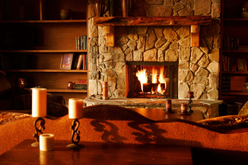 Cozy stone fireplace with crackling fire and rustic wooden shelves perfect for Zoom background Wallpaper