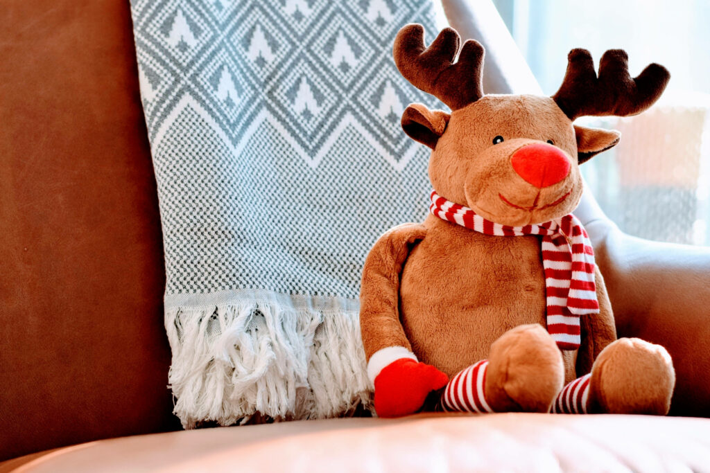 Cozy Stuffed Moose with Festive Scarf on Leather Chair Wallpaper