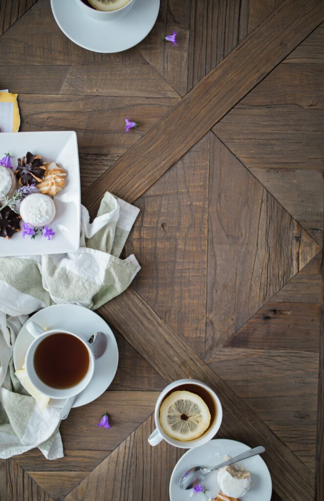 Cozy Tea Party Setup: Cups, Biscuits & Purple Petals on Wood Wallpaper