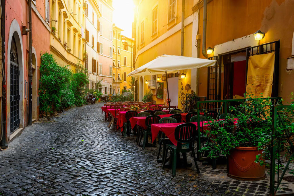 Cozy Trastevere Rome cafe on cobblestone street with colorful buildings red tablecloths sunlight Wallpaper
