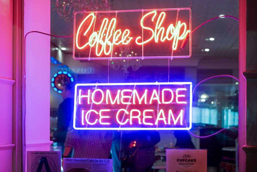 Vibrant neon Coffee Shop and Homemade Ice Cream signs glowing in cozy urban cafe window Wallpaper