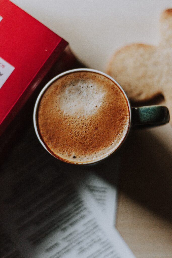 Cozy Cappuccino Wallpaper: Warm Setting with Red Book & Cookie