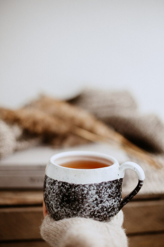 Cozy Wallpaper: Hand Holding Tea Mug in Rustic Warm Setting