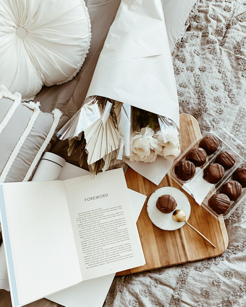 Aesthetic Cozy Scene: White Flowers, Book, Chocolate & Cushions Wallpaper