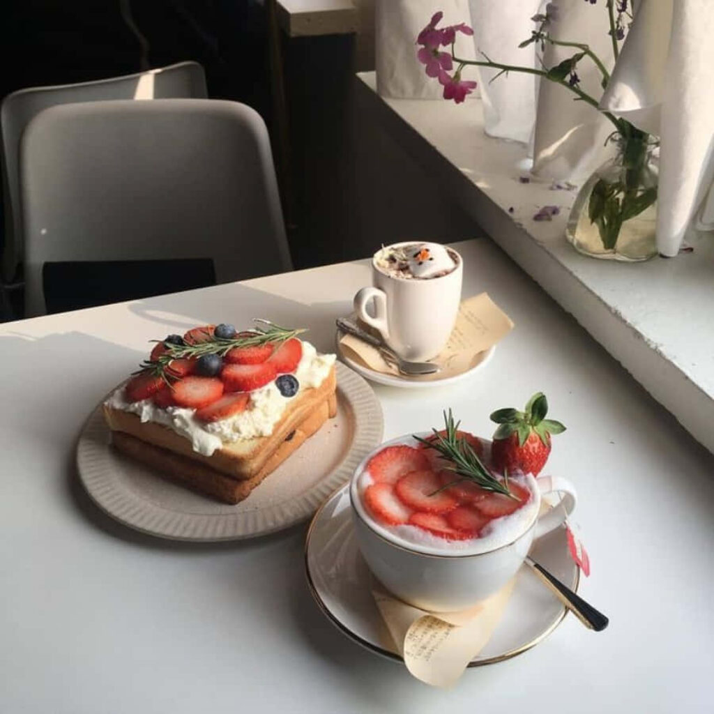 Cozy White Table Setup: Coffee, Cake, and Floral Décor by Window Wallpaper