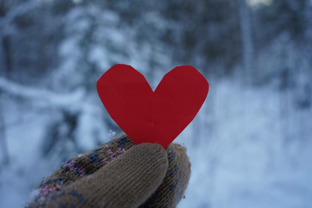 Cozy Winter Scene: Hand in Knitted Gloves with Heart Wallpaper
