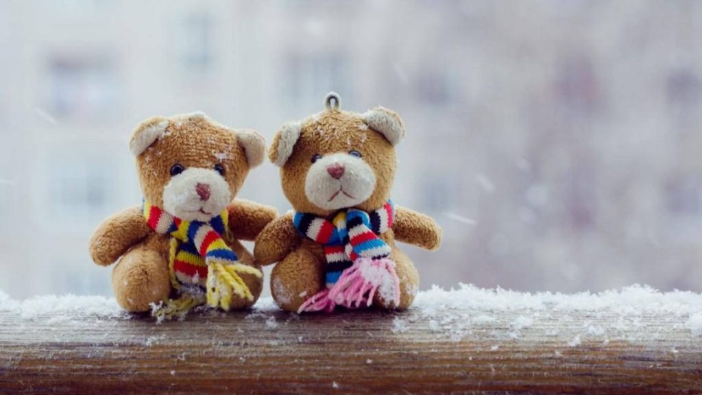 Two brown teddy bears in colorful scarves sitting on snowy railing winter besties wallpaper