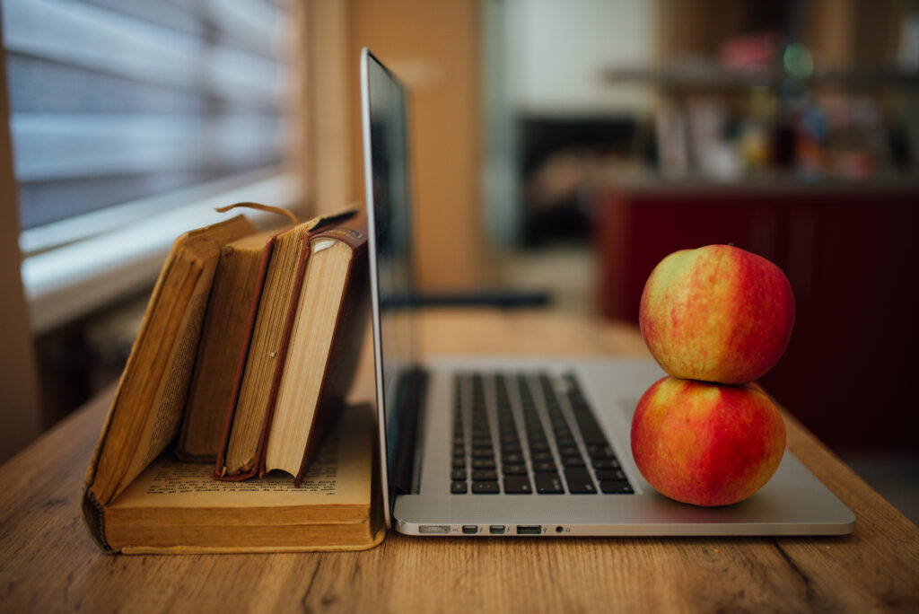 Cozy Workspace: Wooden Table, Laptop, Apples & Books - Warm Wallpaper
