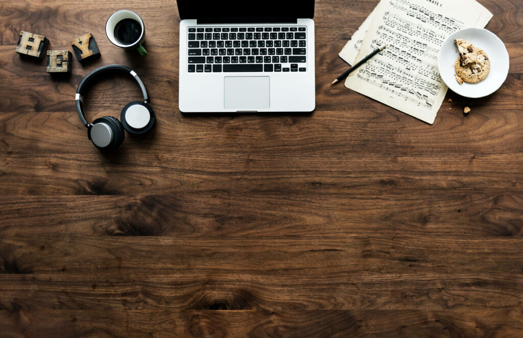 Cozy Workspace Wallpaper: Laptop, Coffee & Music Sheets Background