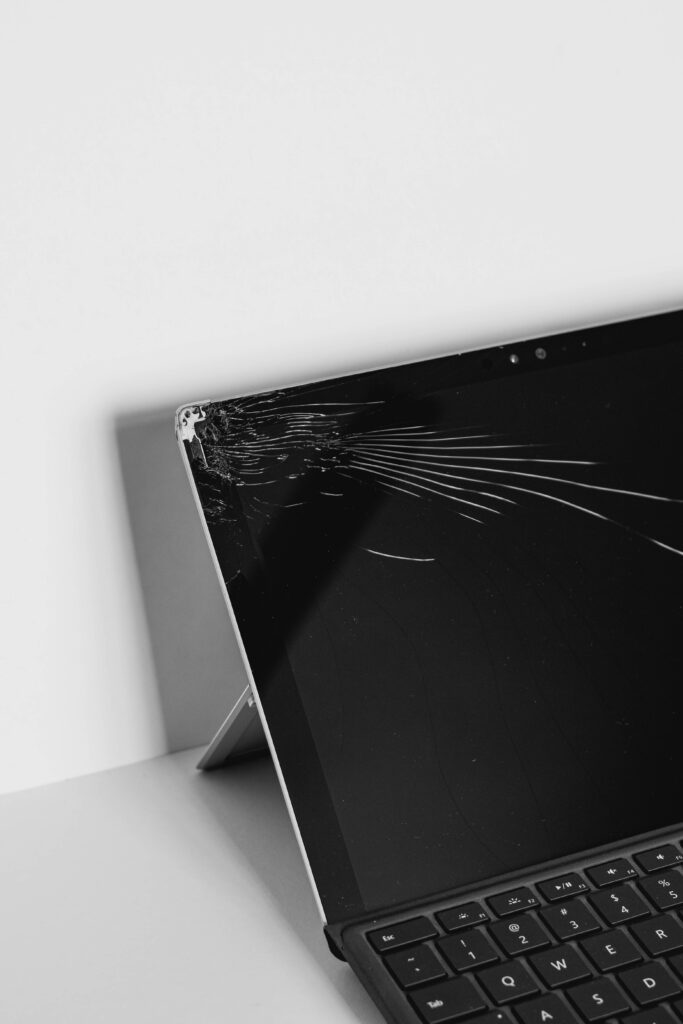 Close-up of laptop with shattered cracked screen corner on black and white background wallpaper