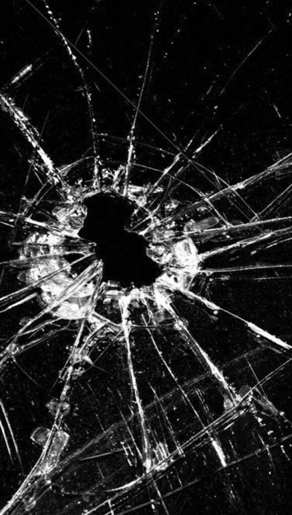 Close-up of cracked smartphone screen wallpaper with sharp shattered glass on black background