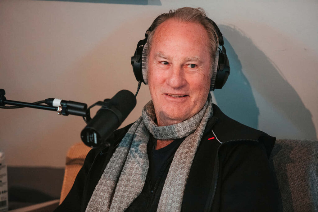 Craig T Nelson recording podcast wearing headphones and patterned scarf in professional studio Wallpaper