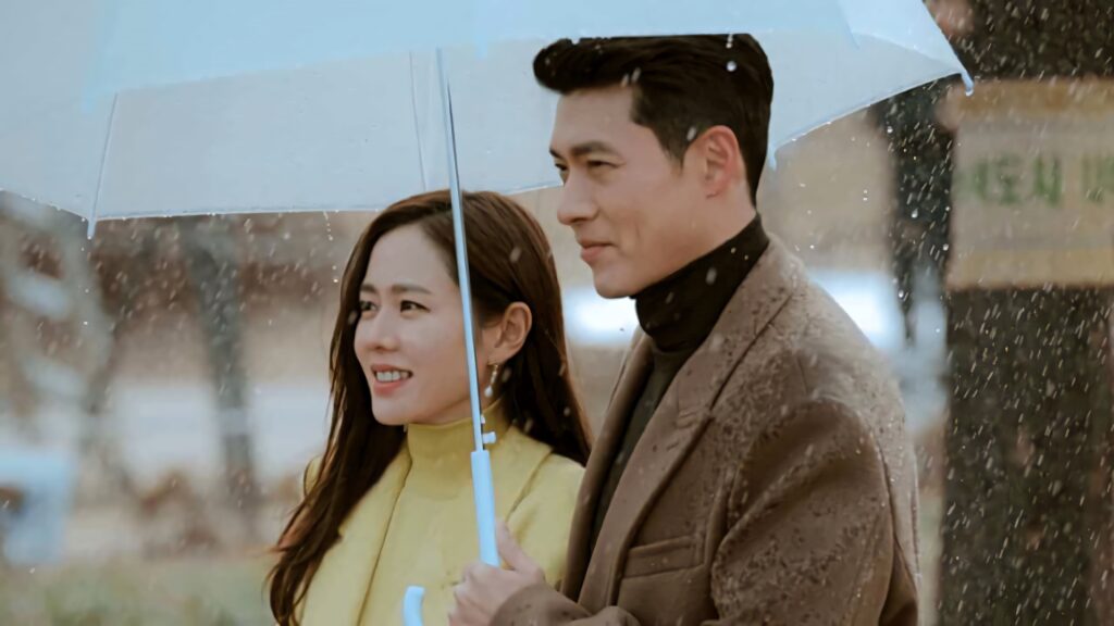 Jeong-hyuk and Yoon Se-ri smiling under umbrella in gentle snow Crash Landing On You wallpaper