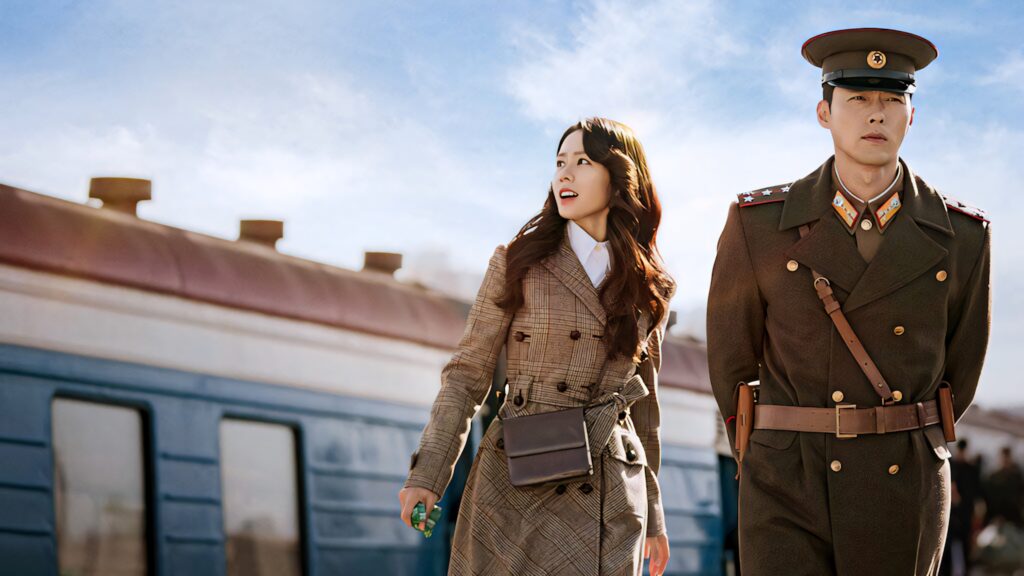 Yoon Se-ri and Ri Jeong-hyeok on sunlit train platform in period outfits Crash Landing On You scene Wallpaper