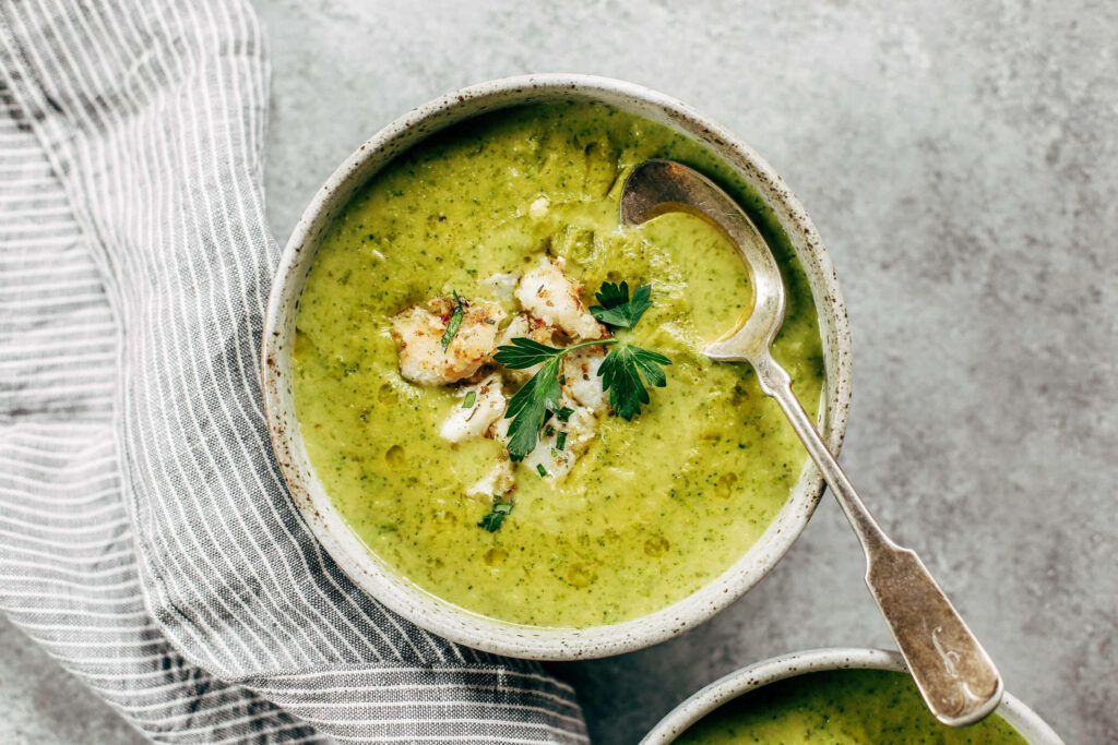 Creamy broccoli chowder with parsley and croutons in rustic bowls and vintage silver spoon Wallpaper