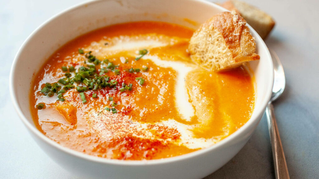 Creamy carrot chowder with chives paprika and rustic bread cozy food wallpaper background