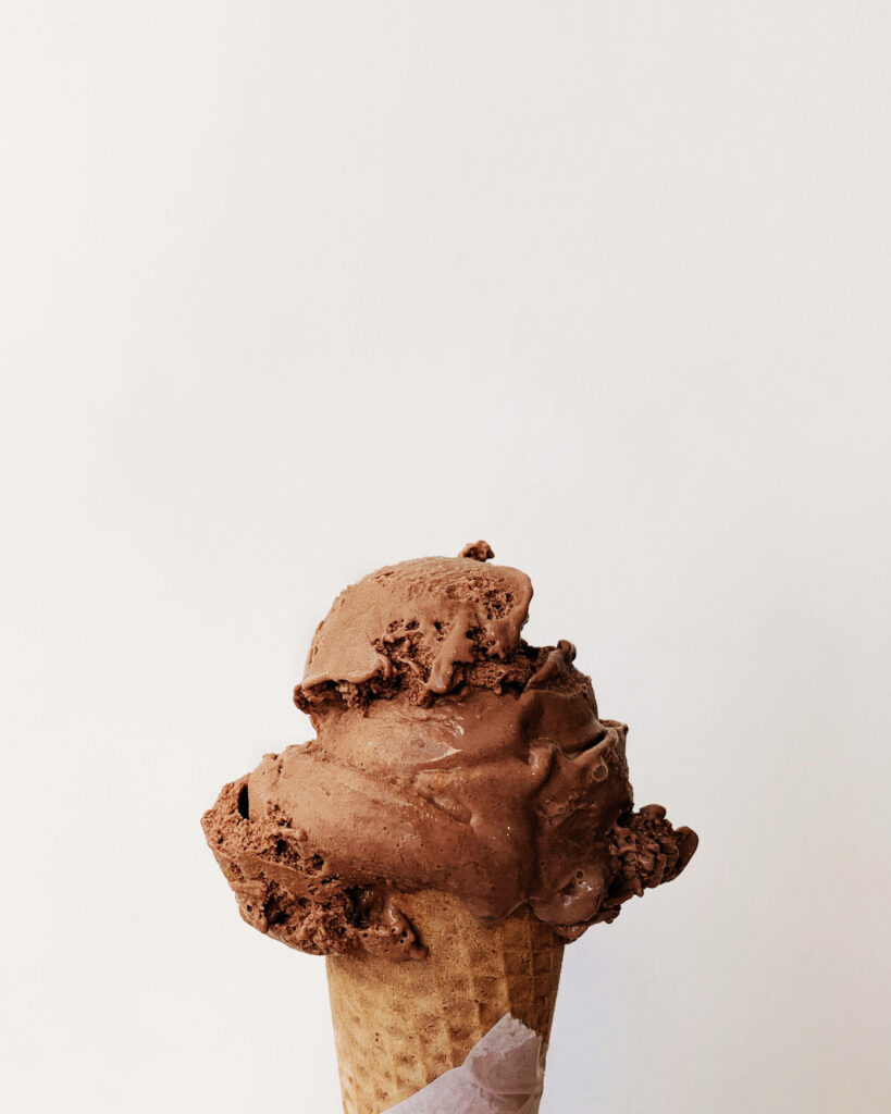 Creamy chocolate ice cream swirled on a crispy waffle cone against white background wallpaper