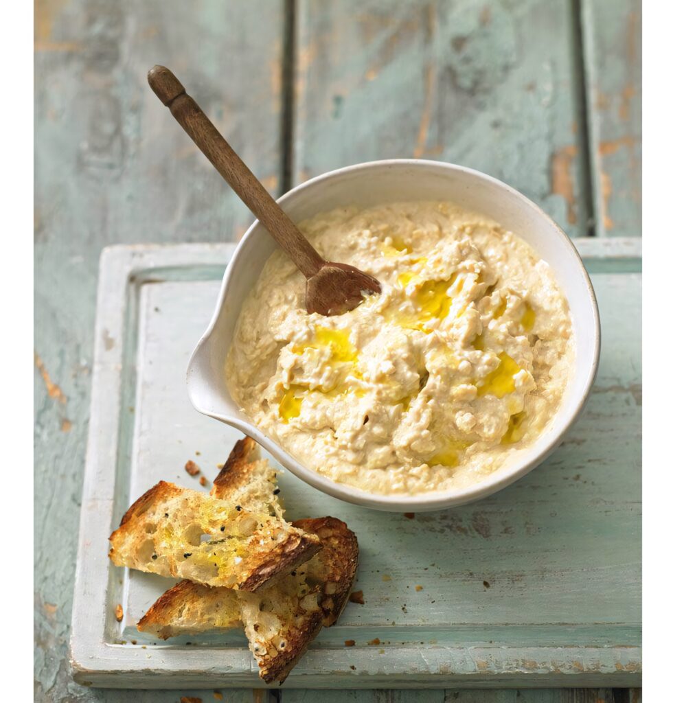 Creamy hummus with olive oil and toasted bread in a rustic bowl on wooden table Mediterranean food Wallpaper