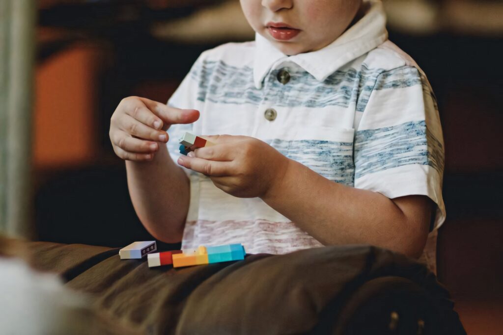 Baby boy playing with colorful Lego blocks wearing striped shirt creativity and play wallpaper