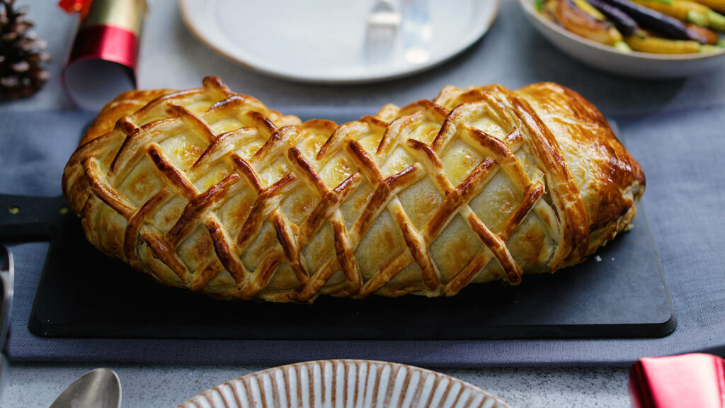 Beef Wellington shaped like a boot with golden flaky pastry and detailed lattice patterns wallpaper