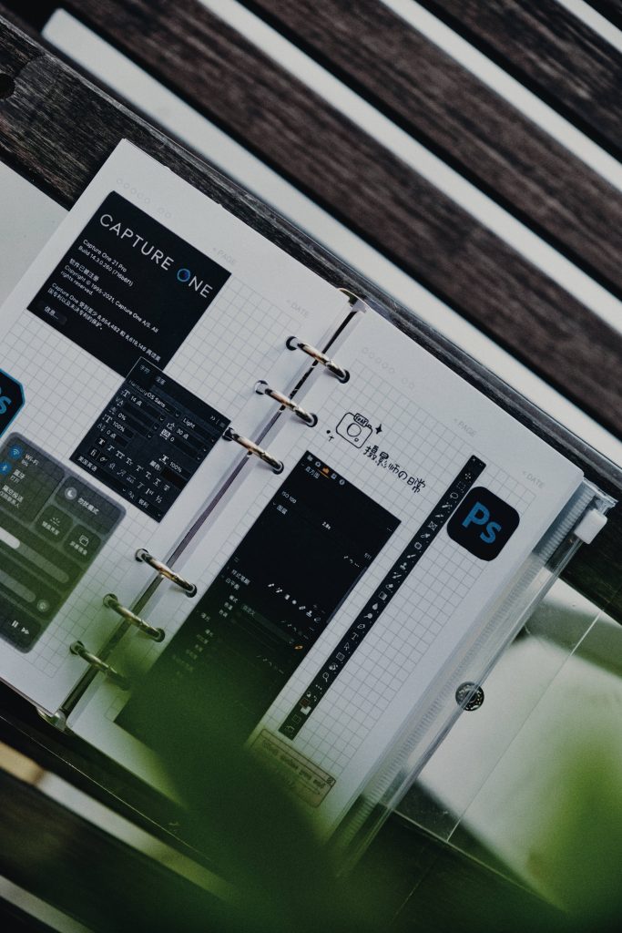 Open planner with Capture One 21 Pro and Photoshop panels on wooden desk for photo editing workflow Wallpaper